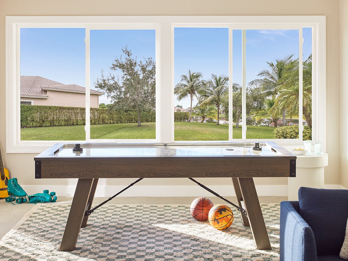a pool table in front of two sets of sliding windows.