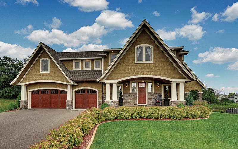 A traditional two-story home with wood-grained front and garage doors