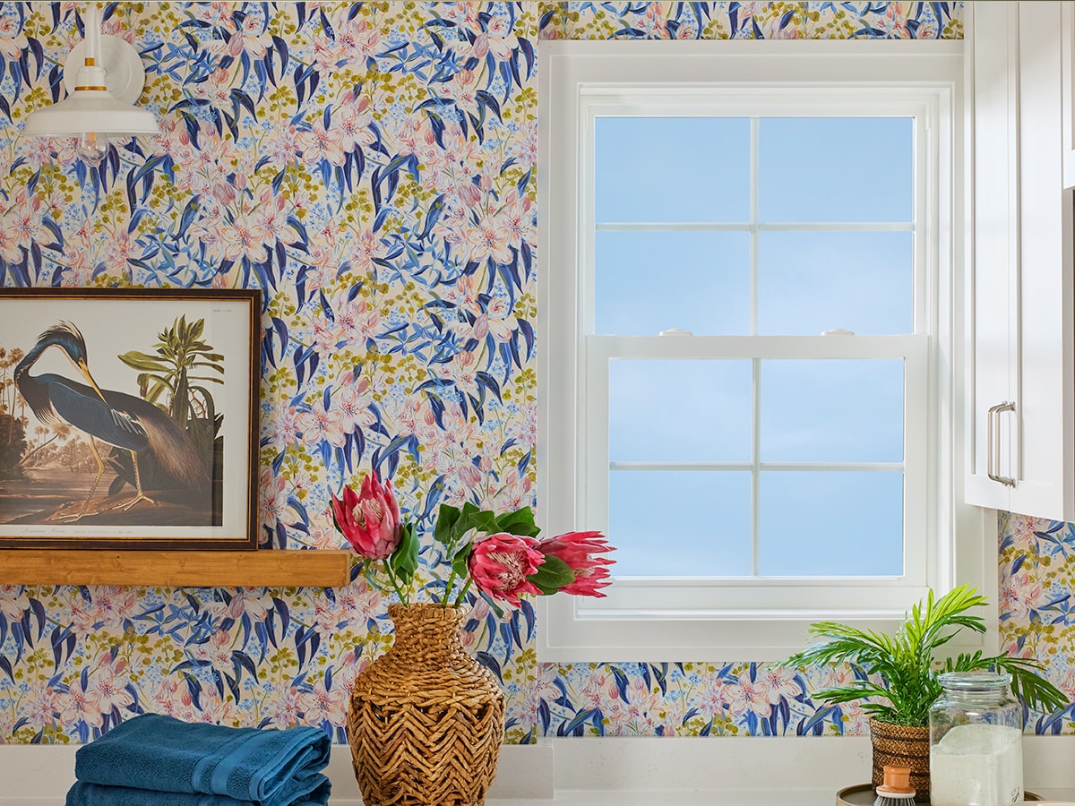 brightly-colored wallpaper in a laundry room with a single white single-hung window