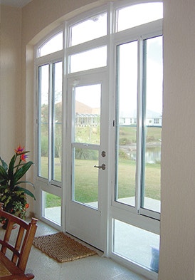 a single hinged door in the middle of a set of fixed frame aluminum windows on a coastal sunroom