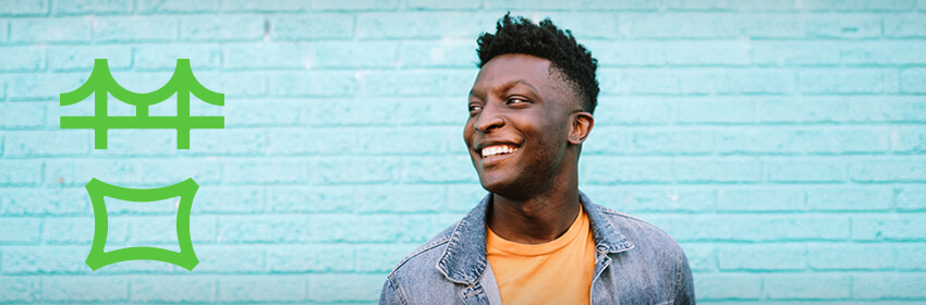 Man smiling as he stands in front of a blue wall.