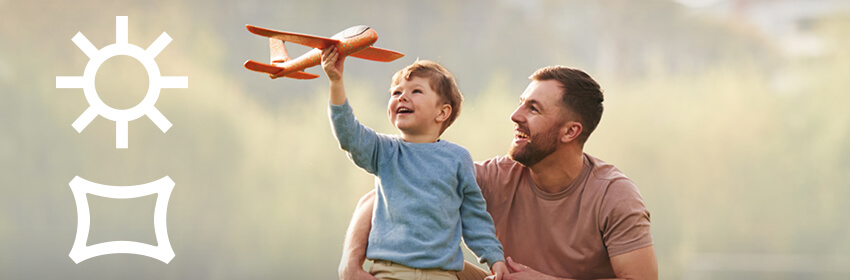 Father and son playing with a model airplane outdoors.