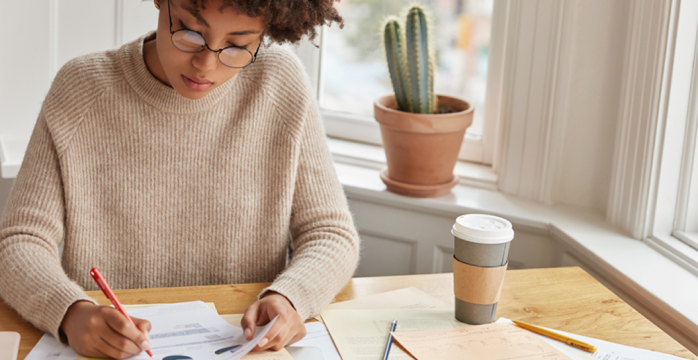 Young woman calculating a personal budget using papers and calculator at her home.
