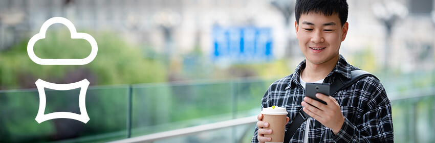 Young man checking his phone while enjoying coffee outdoors.