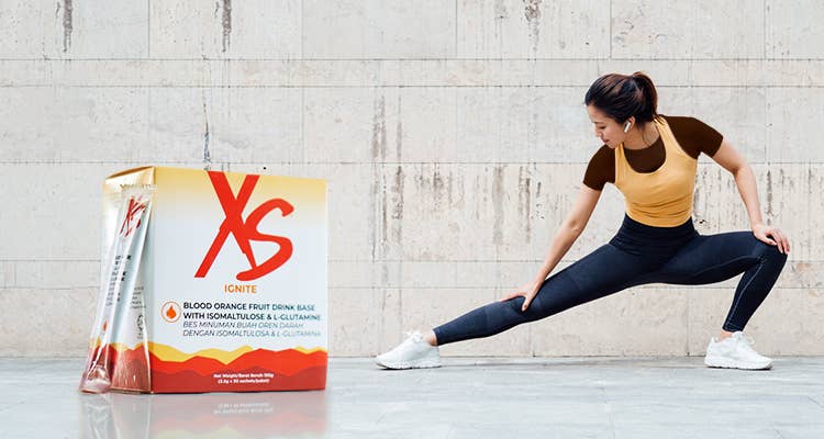 图片显示一位身穿运动装束的健康女性在运动前暖身，旁边为 XS IGNITE 超燃红橙饮含异麦芽酮糖和左旋谷氨酰胺 