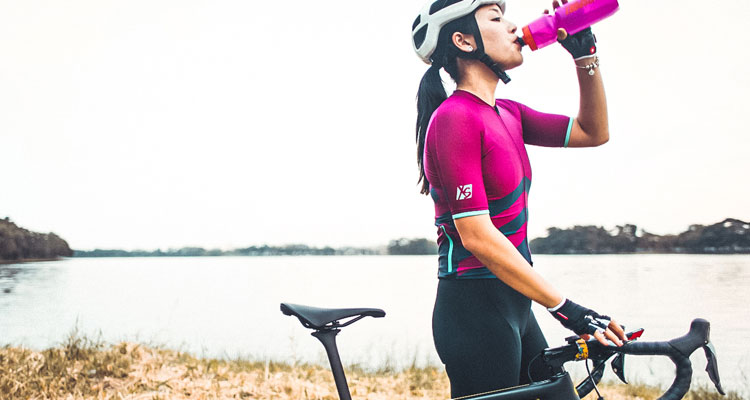 Cyclist drinking from bottle beside a lake
