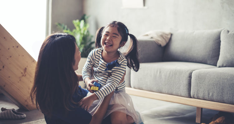 Mother and daughter happily playing in the living room