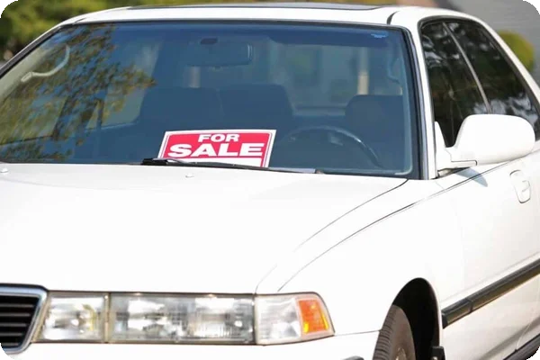a white four door car with a For Sale sign taped to its window