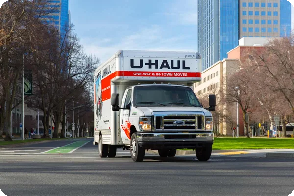 An orange and white U-Haul rental moving truck driving on a highway