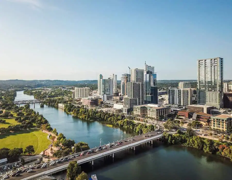 Skyline view of Round Rock, TX with river, bridge, and modern buildings.