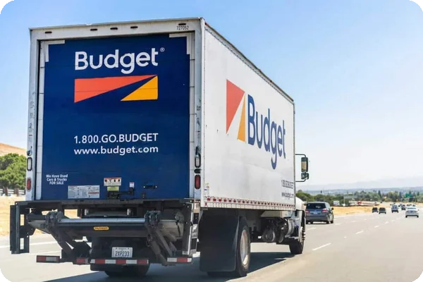A Budget truck, viewed from the back, drives down a highway
