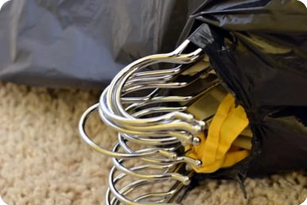 clothes packed up in black trash bags. The hangers are poking out of a hole made in the top of the bags.