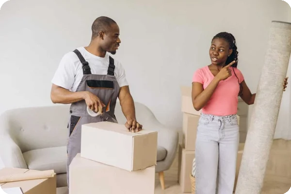 A woman asks a question to a mover who is taping up a box