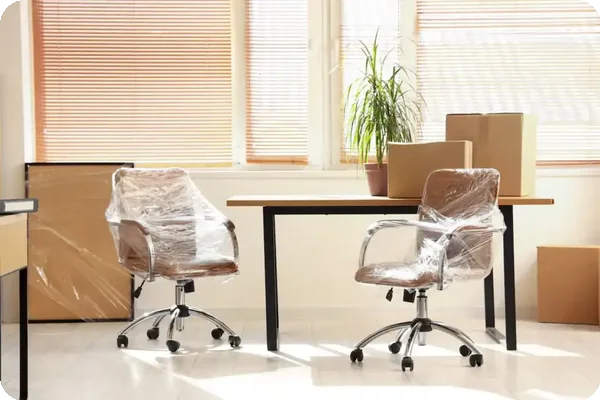 Office chairs wrapped in plastic near boxes during a move
