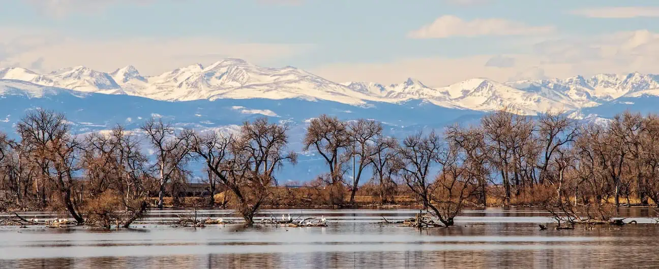 A view of a the lake, trees, and mountains in Barr Lake State Park near Brighton, CO