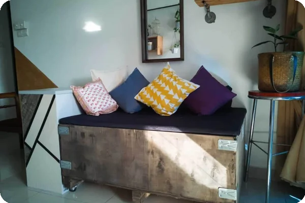 a couch has been upcycled into a smaller seat with cushions using a wooden crate