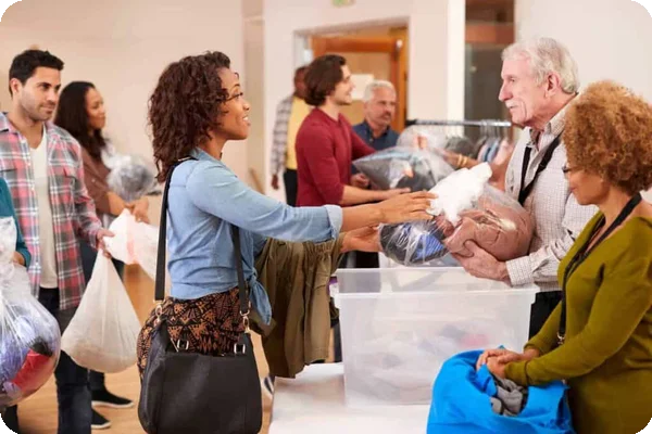 A woman talks to donation center organizers as she hands over a pile of clothing