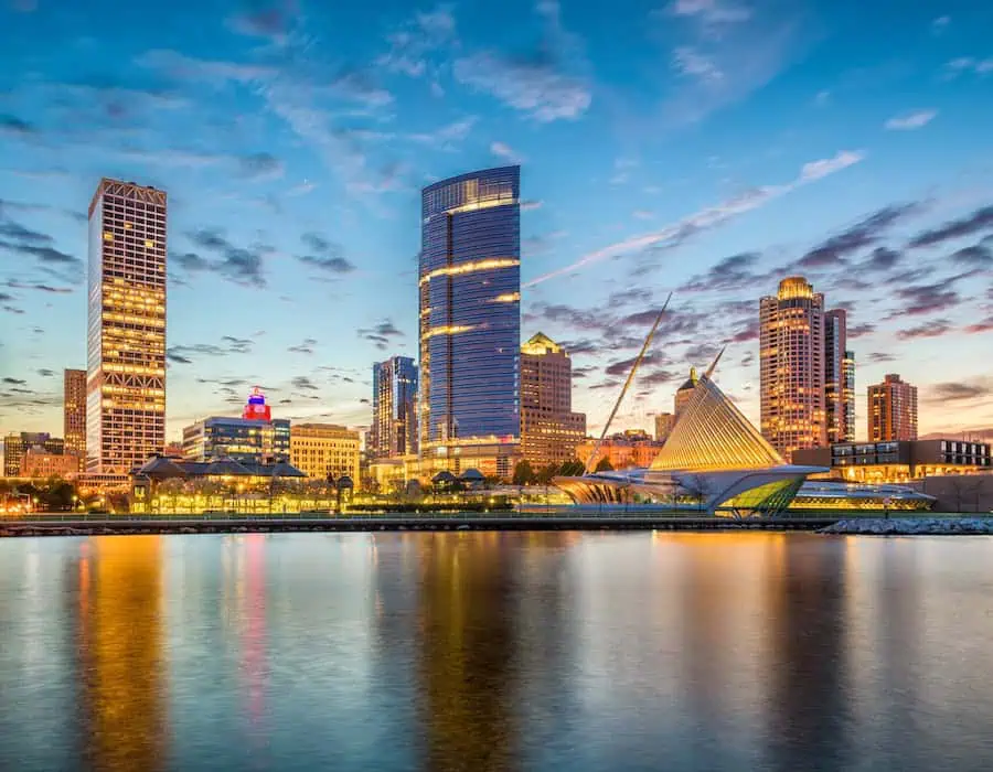 Milwaukee skyline at sunset with the Milwaukee Art Museum and city lights reflected on the water.