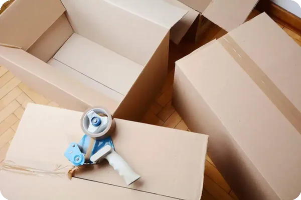 Cardboard moving boxes and packing tape supplies on hardwood floor