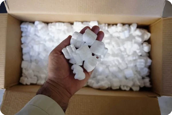 an aerial shot of someone's hand dumping packing peanuts into a box