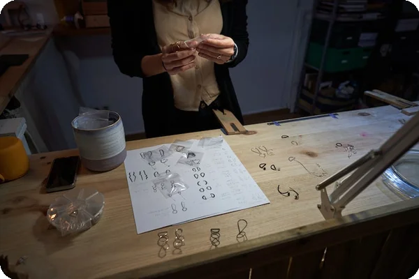 a person catalogues and packs several earrings set out on a table
