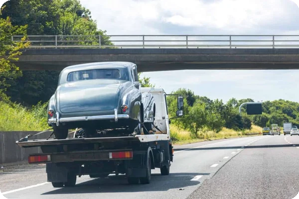 A vintage car on a tow truck being transported