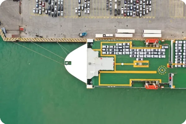 Cars are loaded onto a large ship for transport overseas