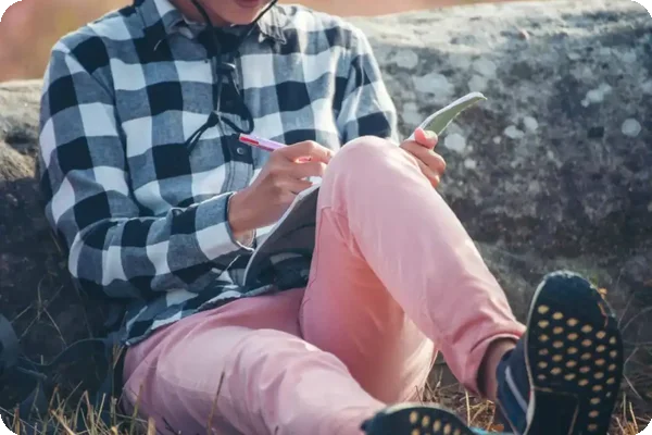 Person sitting outdoors making a list.