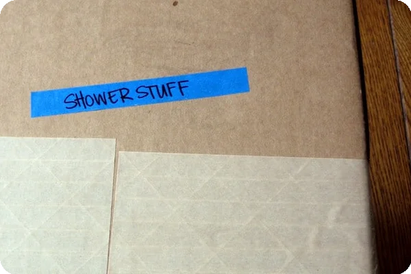 A cardboard box has a piece of blue tape on its side labeled clearly