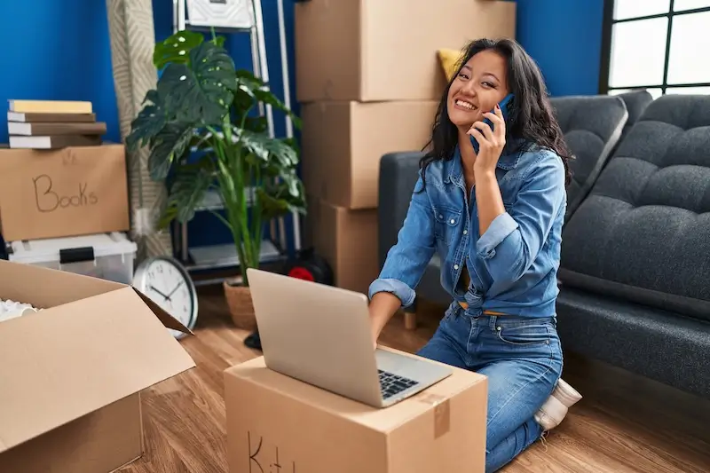 Image of a woman smiling on the phone with boxes next to her