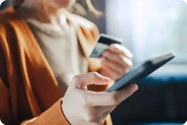 Woman holding credit card while making payment on smartphone.