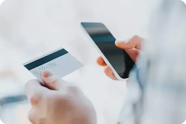 Person holding a debit card and smartphone to manage relocation expenses.