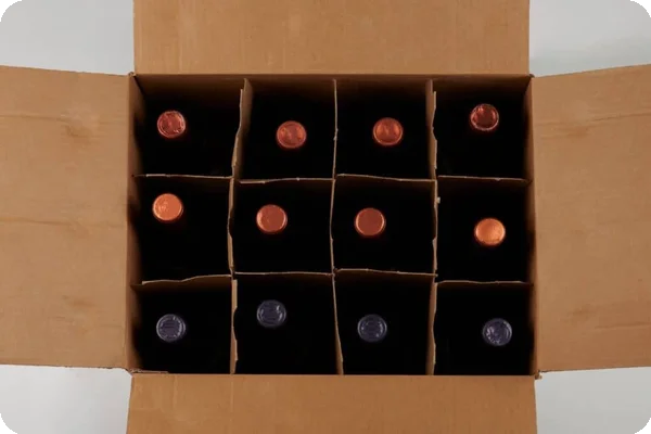wine bottles sit in each section of a divided insert in a box. Only the very tops of the foil around the bottles' corks can be seen.