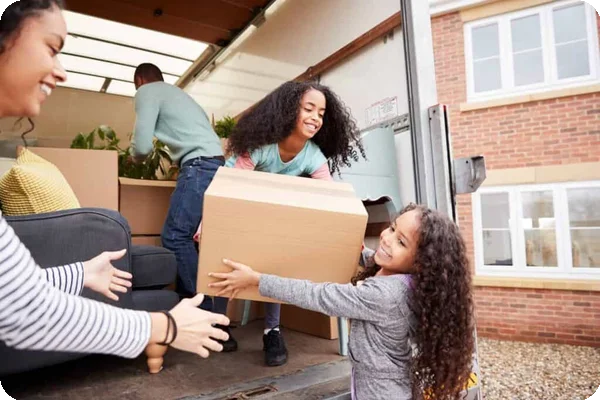 Two young children help their parents load a moving truck