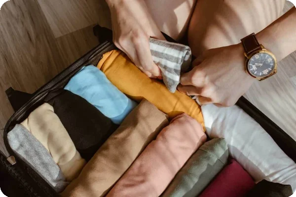Someone adds a rolled up t-shirt to a suitcase already packed with other rolled up clothing