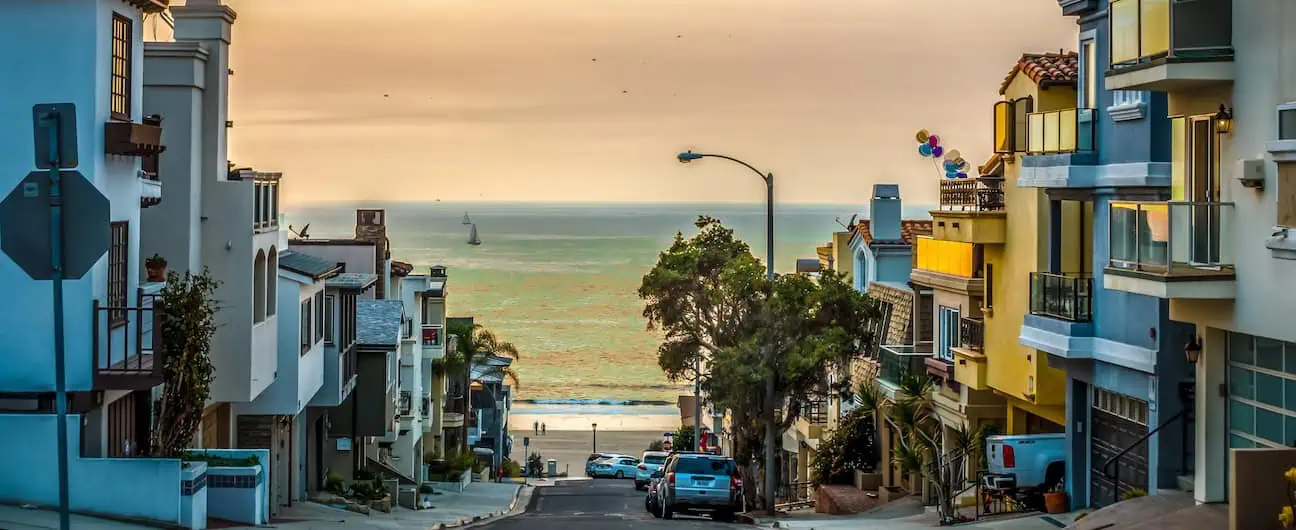 A view of a street lined with houses that leads to a beach at Huntington Beach, CA