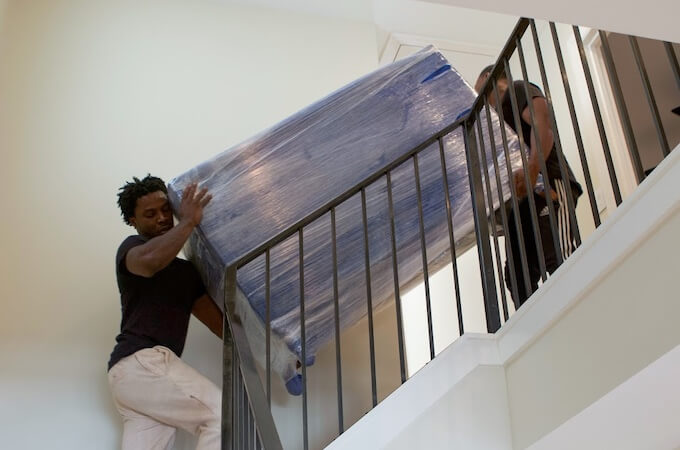 Movers carrying a couch down stairs