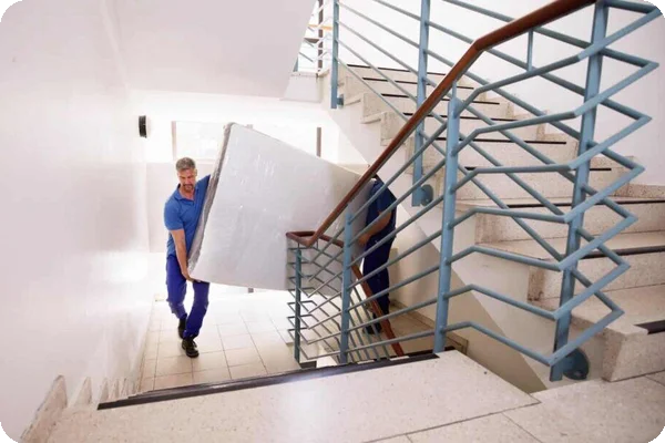 Two movers carry a mattress up a flight of stairs