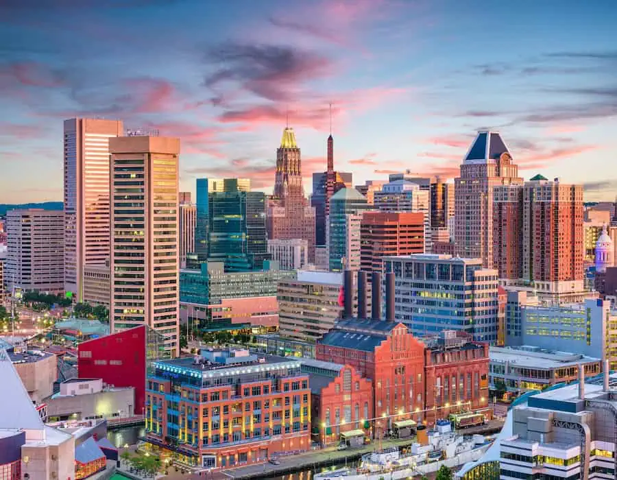 Panoramic view of downtown Baltimore, Maryland, with modern buildings under a pink and blue evening sky.