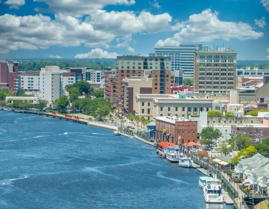 Aerial view of Wilmington, North Carolina, historic district along the Cape Fear River with a cloudy sky.
