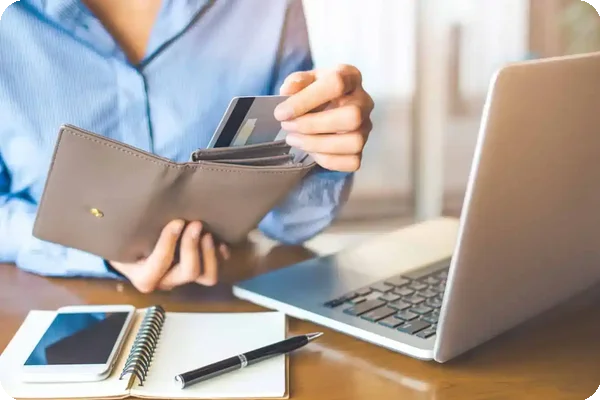 Person holding wallet with multiple credit cards while updating address with credit card companies after a move.