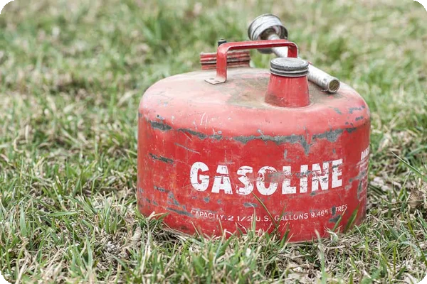 a red can of gasoline sits on a lawn