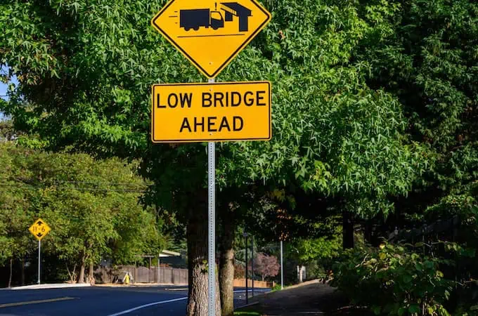 A warning sign on a street of a low bridge ahead