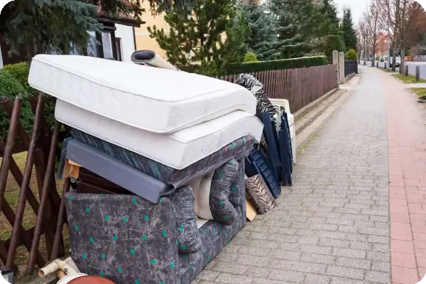 Rubbish left on the road, including mattresses and old furniture.