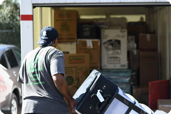 Professional movers loading household belongings into a portable moving container in a driveway