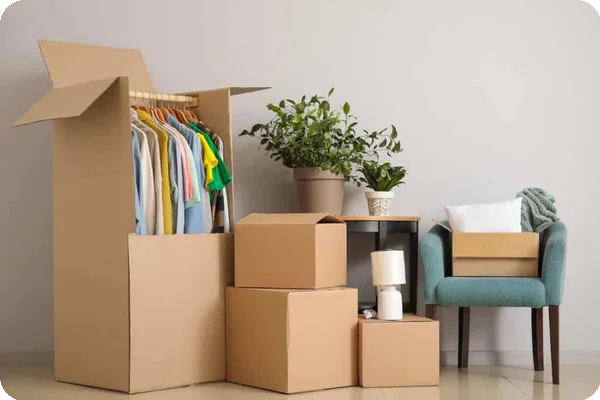 A wardrobe box and several other types of boxes sit near a wall