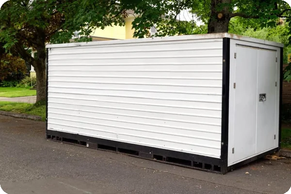 a white moving container sitting on a residential street, waiting to be loaded