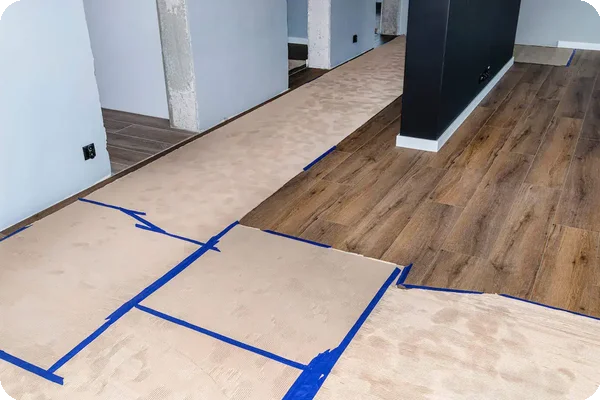 Cardboard floor protection taped down to prevent water damage during a rainy day move.