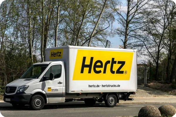 A yellow Hertz truck is parked on the side of a road