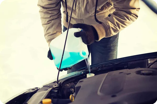 A person checking the engine fluids, antifreeze, and wiper fluid on a rental moving truck before a winter trip